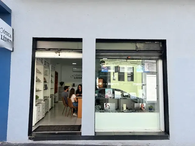 Entrada da Ótica Líder na Rua das Óticas, com clientes no balcão