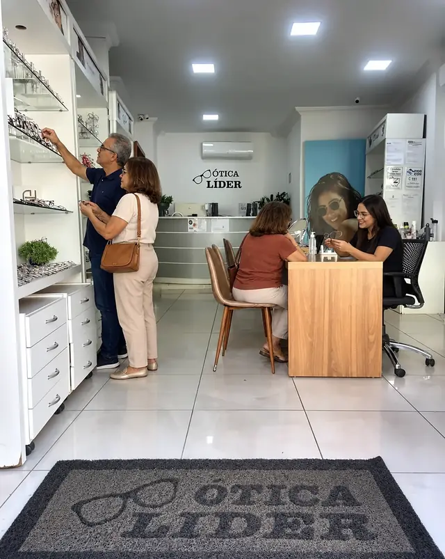 Interior da Ótica Líder com atendimento na mesa e clientes nos expositores